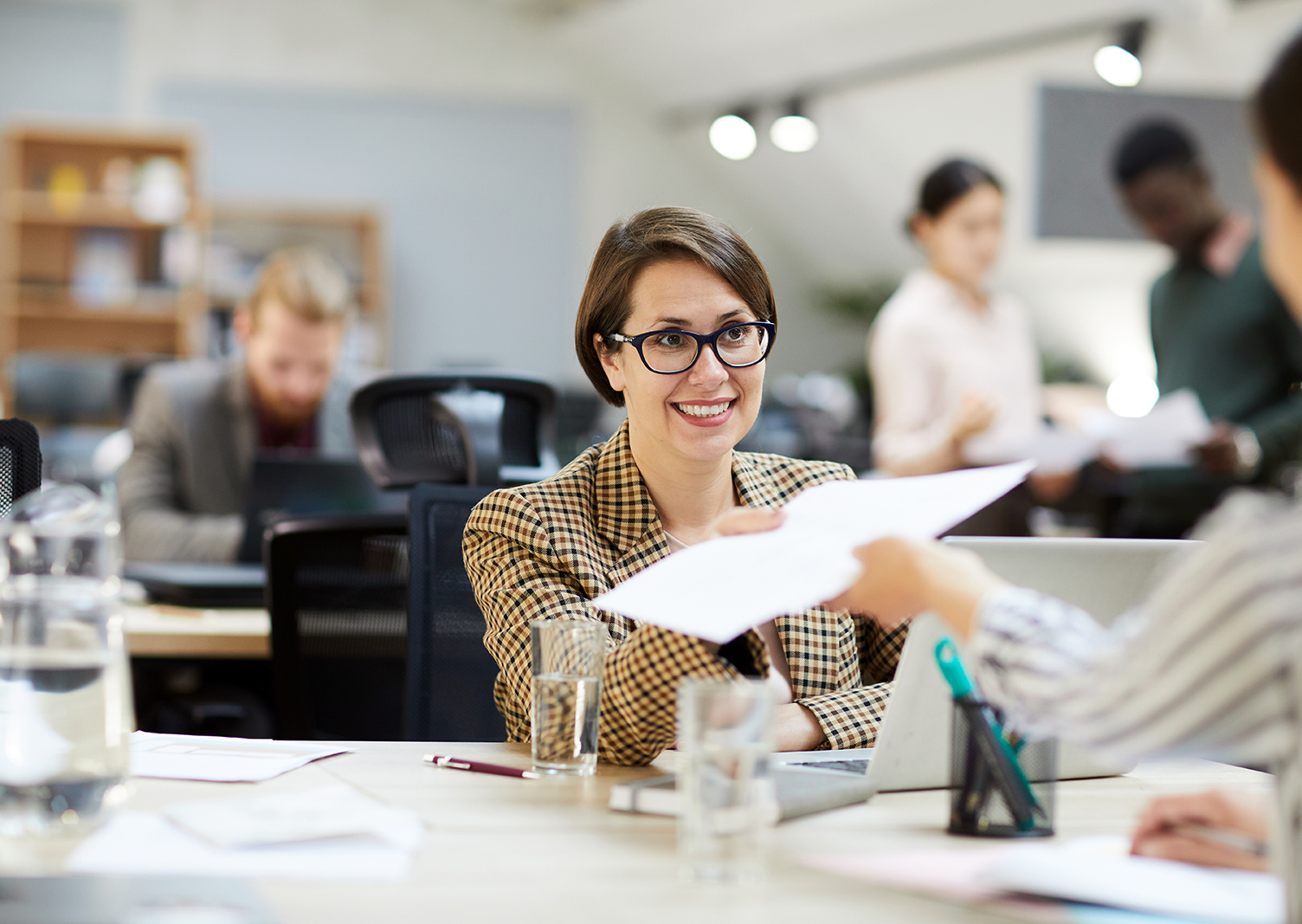 smiling-businesswoman-giving-documents-to-YLNUKBJ.jpg